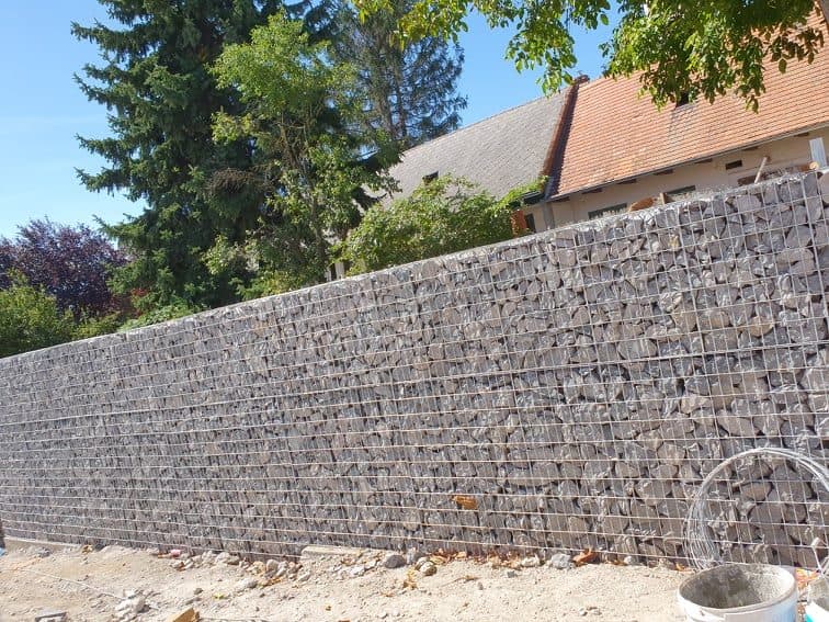 Fertige Gabionenwand aus Naturstein entlang eines Grundstücks