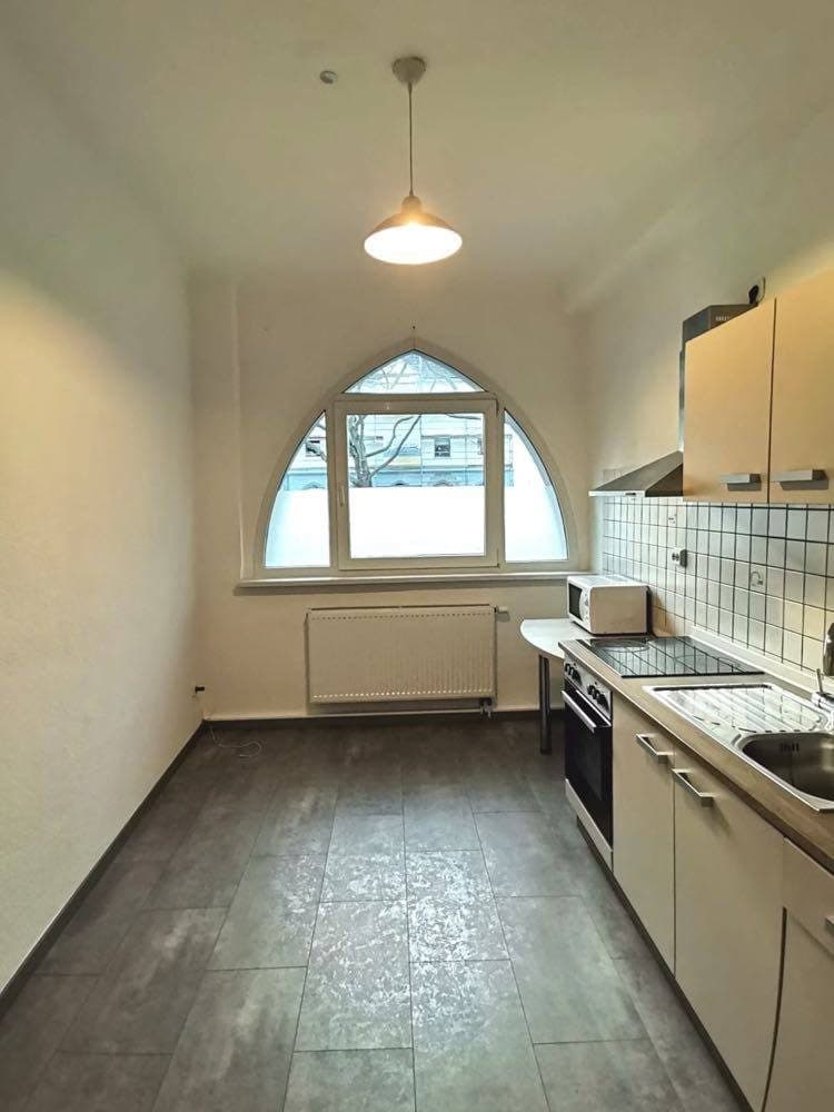 Neue Küchenzeile mit Backofen unter einem Rundbogenfenster