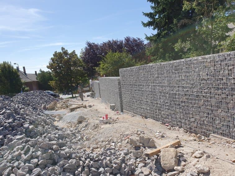 Gabionenwand im Aufbau mit angeliefertem Naturstein im Vordergrund
